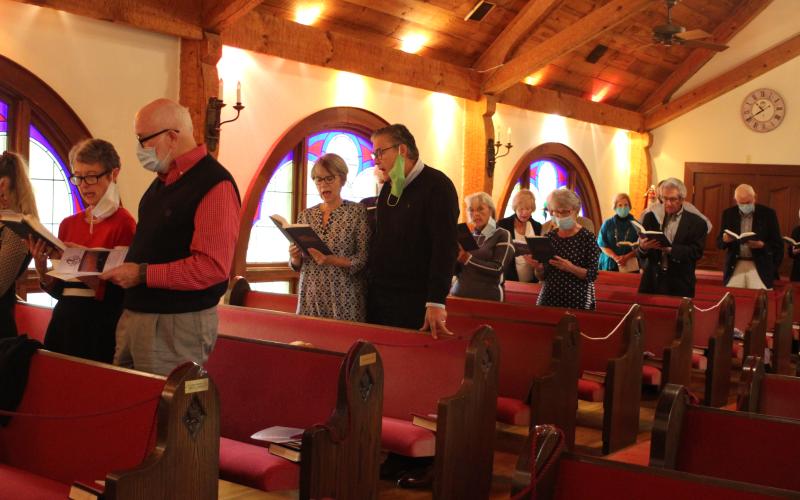 Megan Broome/The Clayton Tribune. The congregation stands and sings hymnals at a church service and special 40th Anniversary celebration of the Tom McClure Memorial Chapel in Sky Valley Sunday.