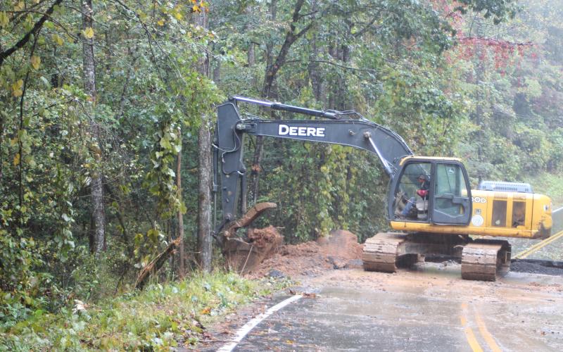 Megan Broome/The Clayton Tribune. The Rabun County Road Department packs dirt and rocks Sunday to rebuild part of the road on Warwoman Rd. just past Earls Ford Rd. that was washed away from the storm.