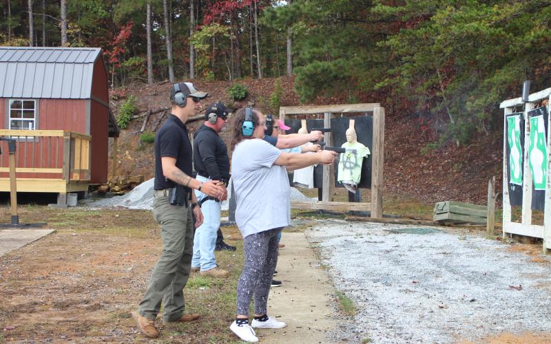 Megan Broome/The Clayton Tribune. Deputy Ryan Brown helps Jonnie Brown with her technique for shooting at moving targets last Saturday.
