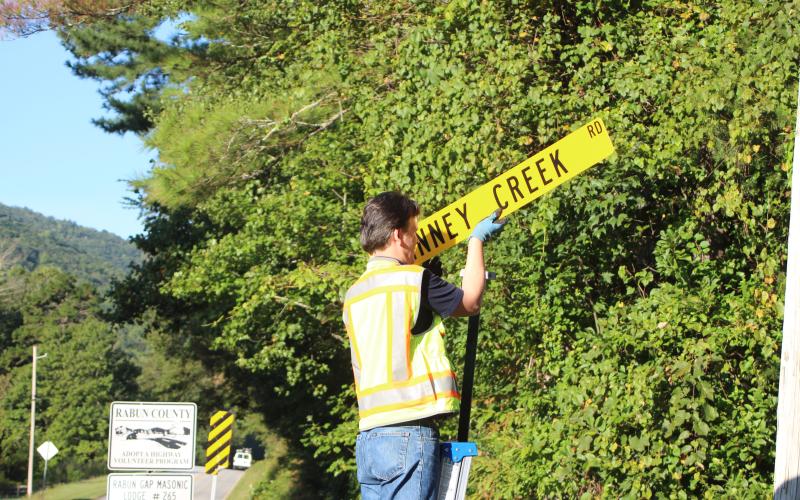 Megan Broome/The Clayton Tribune. Keith Yunger, sign technician for the Rabun County mapping department, replaces one of the road name signs located on Warwoman Rd. that was stolen on Labor Day weekend.