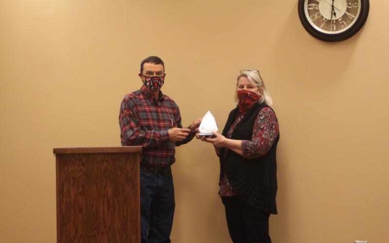 Megan Broome/The Clayton Tribune. Board of Education Chairman Steve Cabe, left, presents an award to Tax Commissioner Sandy Smith at last Thursday’s meeting. The award was presented on behalf of Board of Education members to thank Smith for her hard work during her career.  Her department’s tax collections contribute to the amount of funding Rabun County Schools receives, Superintendent April Childers explained. Smith is retiring at the end of the year.
