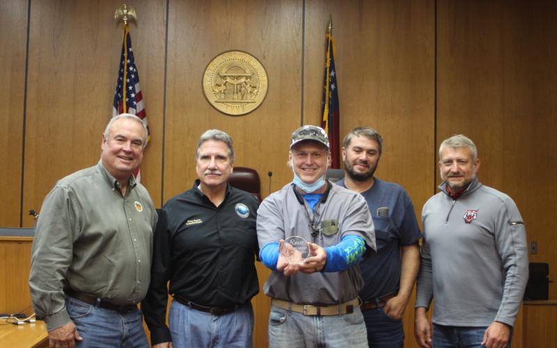 Megan Broome/The Clayton Tribune. Commissioners Kent Woerner, left, chairman Gregg James, Will Nichols, and County Administrator Darrin Giles present Stephen Arbitter (center) with an award for his 8 years of service as a commissioner at last Tuesday’s meeting. It was Arbitter’s last meeting before vacating his seat.