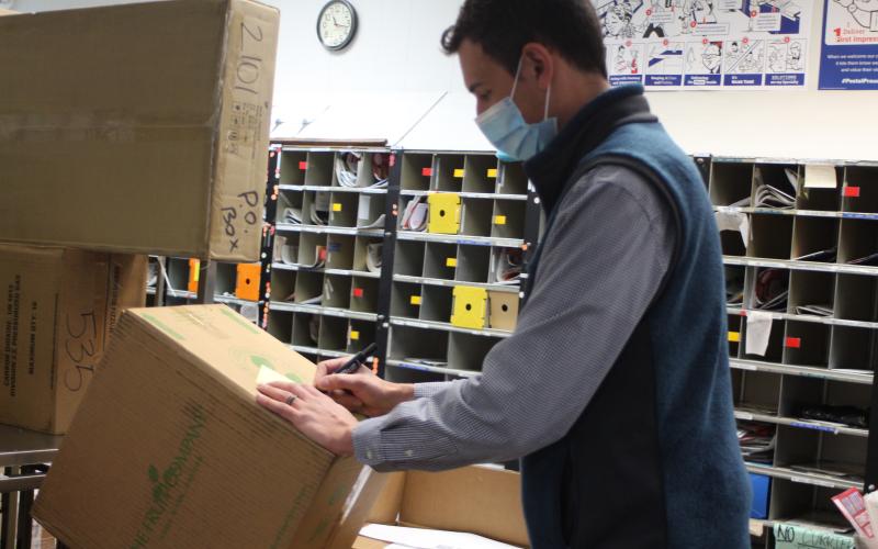 Megan Broome/The Clayton Tribune. Colby Nichols, acting supervisor at the Clayton Post Office, sorts packages that the USPS is receiving in large volumes during the holiday season.
