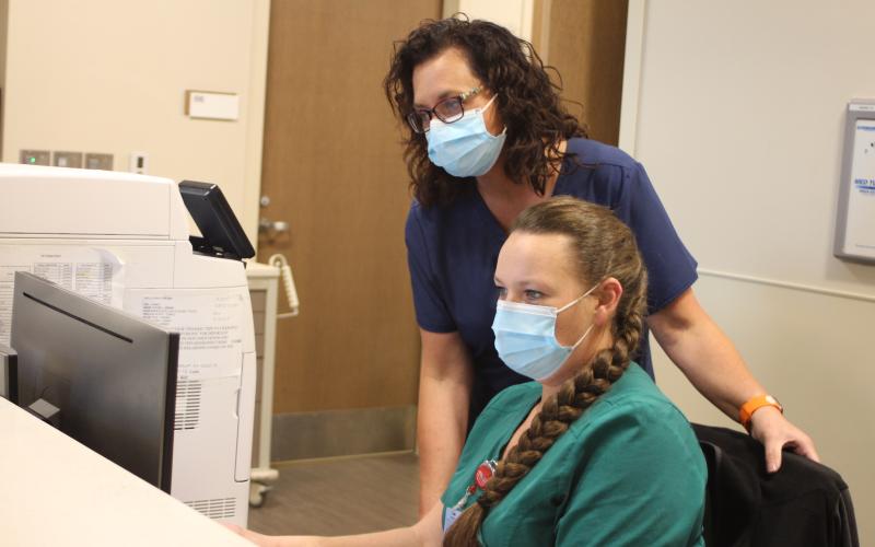 Megan Broome/The Clayton Tribune. Mandy Hopkins, director of performance improvement and care coordination at Mountain Lakes Medical Center (MLMC), left, and Hope Brown, patient care technician in the MLMC emergency department, review a patient's chart in the emergency department at Mountain Lakes Medical Center.