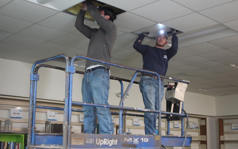 Megan Broome/The Clayton Tribune. Jacob Reynolds, left, and Payton Hunter with Hunter Electric install LED lights at the Rabun County Library. Frick said that this new lighting will be more energy-efficient.