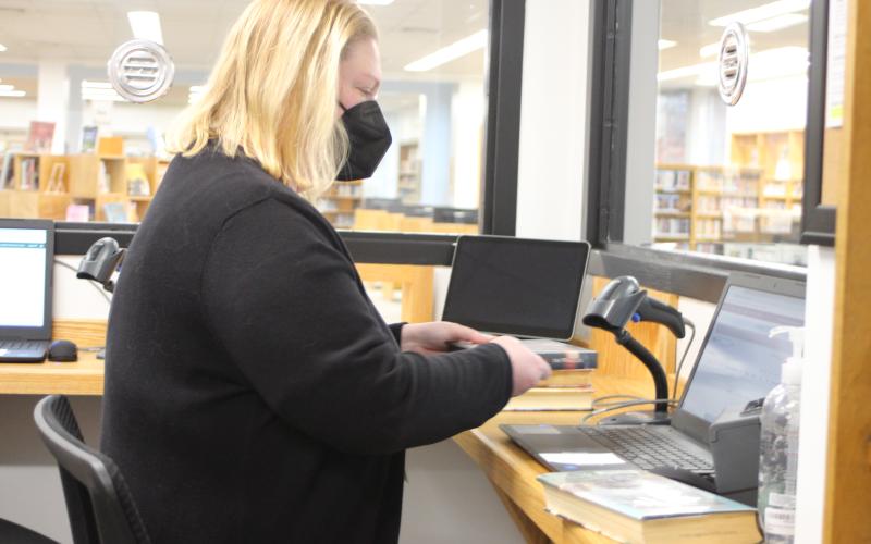 Megan Broome/The Clayton Tribune. Senior Clerk Melissa Poslusny sorts and checks-in inventory behind the newly-renovated circulation counter at the library on Tuesday.