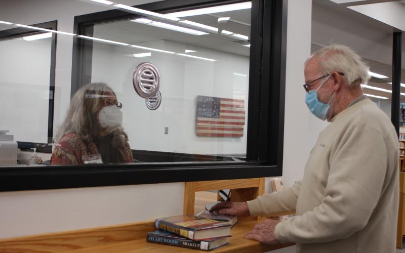 Megan Broome/The Clayton Tribune. Circulation Clerk Peggie Wilcox, left, checks out a library patron at the new circulation counter on Tuesday.