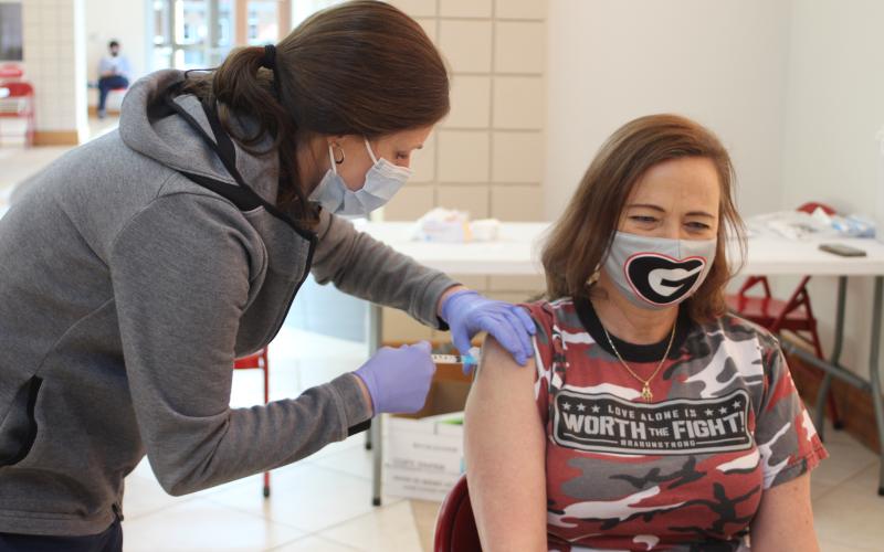 Megan Broome/The Clayton Tribune. Carla Kilby, second grade teacher at the Primary School, right, receives a Moderna vaccine from Gwen Stiles, RN in the OR and outpatient services at Mountain Lakes Medical Center, at last Friday’s vaccine clinic held in the Rabun County Schools Fine Arts Building.