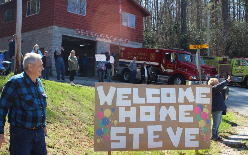 Megan Broome/The Clayton Tribune. Friends and family of former Satolah Fire Department Chief Steve Wilson gathered at the Satolah Fire Station Tuesday to welcome him home after a months-long battle being hospitalized with COVID-19. Jimmy Nix stands beside the homemade sign and cheers for Wilson along with other friends and family members.