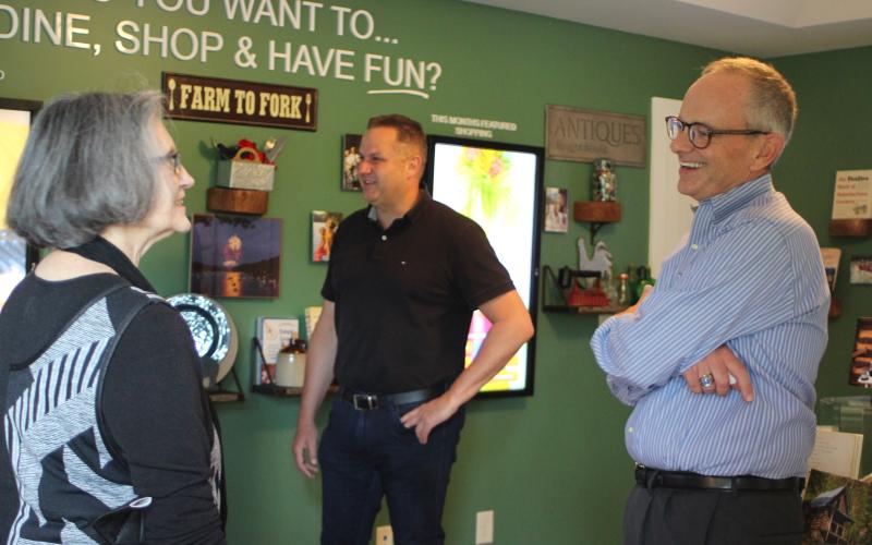 Megan Broome/The Clayton Tribune. Anita Pittman, left, and Todd Webb, COO of ELK Group International, converse with new Chamber President Cliff Bussard at a meet-and-greet at the Rabun County Welcome Center on Monday.