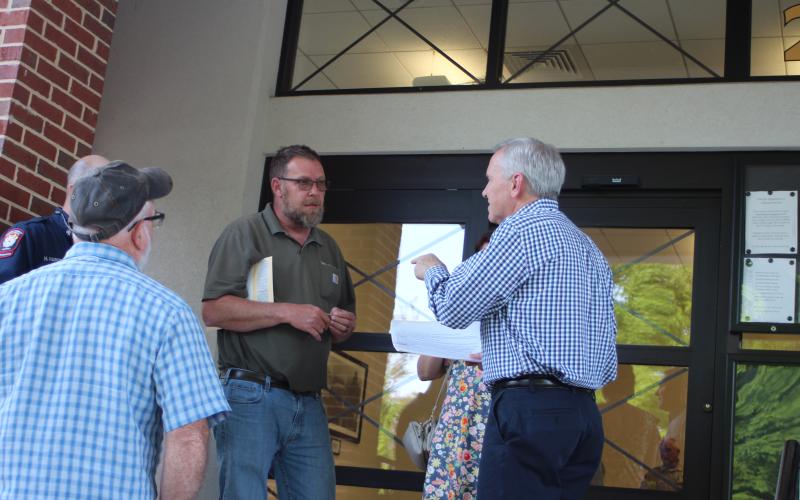 Megan Broome/The Clayton Tribune. Lake Burton resident Gerald Hulett has a passionate discussion with Planning and Zoning Officer Les Neely about the commissioners vote to approve the rezoning request from Agricultural to Commercial Business for a property on Bridge Creek Rd., on the courthouse steps Tuesday.