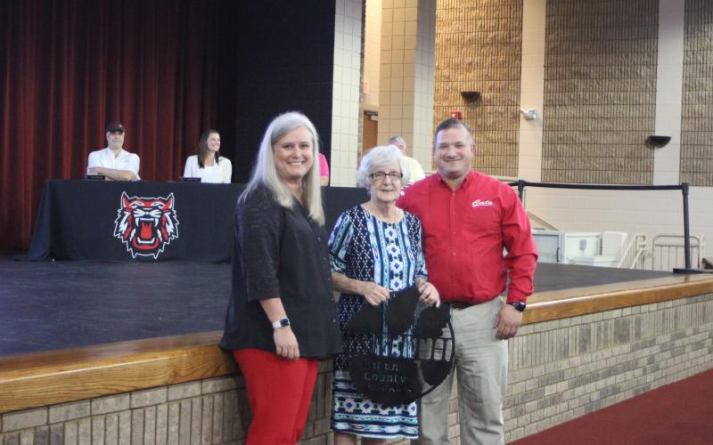 Megan Broome/The Clayton Tribune. Superintendent April Childers, left, and Transportation Director Marty Dixon recognize bus driver Judy Smith for her retirement from the Transportation Department at the 2020-2021 retired employee reception last Thursday. Each employee received a customized sign made by the agriculture class.