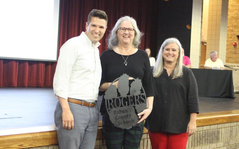 Megan Broome/The Clayton Tribune. RCHS Principal Justin Spillers, left, and Superintendent April Childers recognize Spanish Teacher Norma Rogers for her retirement from RCHS at the 2020-2021 retired employee reception last Thursday. Each employee received a customized sign made by the agriculture class.