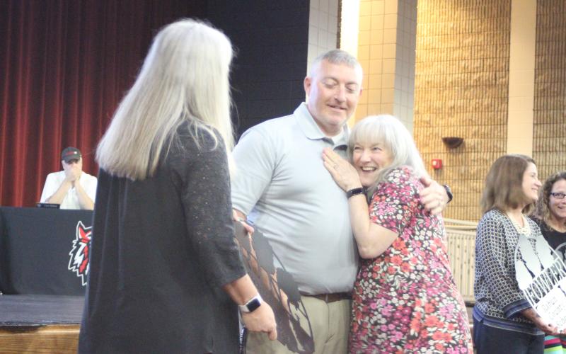 Megan Broome/The Clayton Tribune. Superintendent April Childers, left, and RCES Jonathan Welch receive hugs from retired sixth grade teacher Yvonne Ring as she is recognized at the 2020-2021 retired employee reception held at RCHS last Thursday.