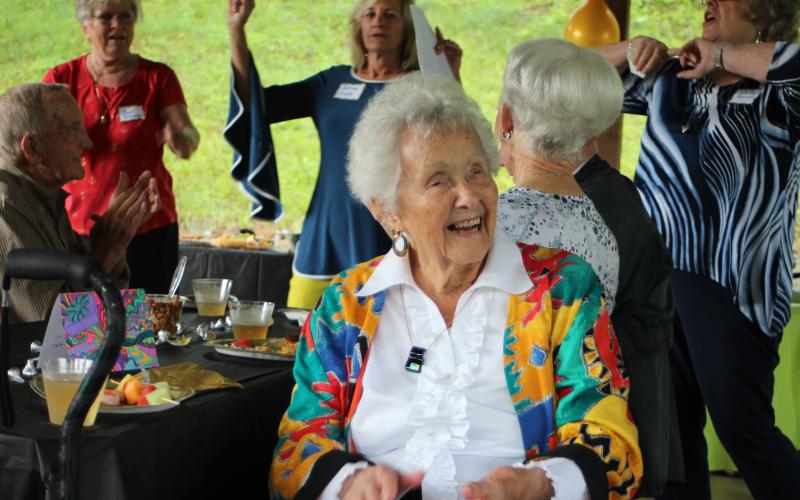 Megan Broome/The Clayton Tribune. Sky Valley resident Louise Kail smiles and cheers as a crowd of friends and family members sing her happy birthday for her 100th birthday at her party in Sky Valley on Sunday.