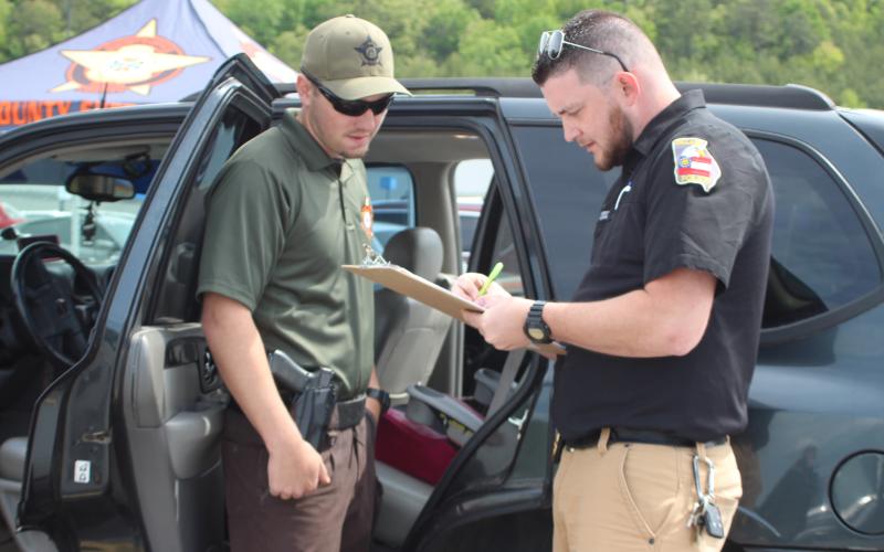 Megan Broome/The Clayton Tribune. Rabun County Sheriff's Office Patrol Corporal Clinton Scott, left, and Dillard Police Chief Jeremy Parker participated in a car seat inspection event at the Clayton Walmart recently where nationally certified technicians helped citizens properly install car seats and booster seats. The RCSO partnered with Safe Kids Rabun County for the event. Scott was one of five deputies who became certified as a Child Passenger Safety Technician (CPST).