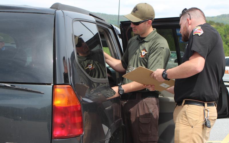 Megan Broome/The Clayton Tribune. Rabun County Sheriff's Office Patrol Corporal Clinton Scott, left, and Dillard Police Chief Jeremy Parker participated in a car seat inspection event at the Clayton Walmart recently where nationally certified technicians helped citizens properly install car seats and booster seats. The RCSO partnered with Safe Kids Rabun County for the event. Scott was one of five deputies who became certified as a Child Passenger Safety Technician (CPST).