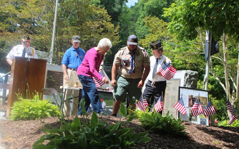 Megan Broome/The Clayton Tribune. Wilma Hoilman places a flag to honor the memory of a veteran close to her who has passed away at Monday’s Memorial Day ceremony. Also pictured are Col. (Ret.) Guy Gober, who was the guest speaker, left, and Eagle Scout Dominic Cross.