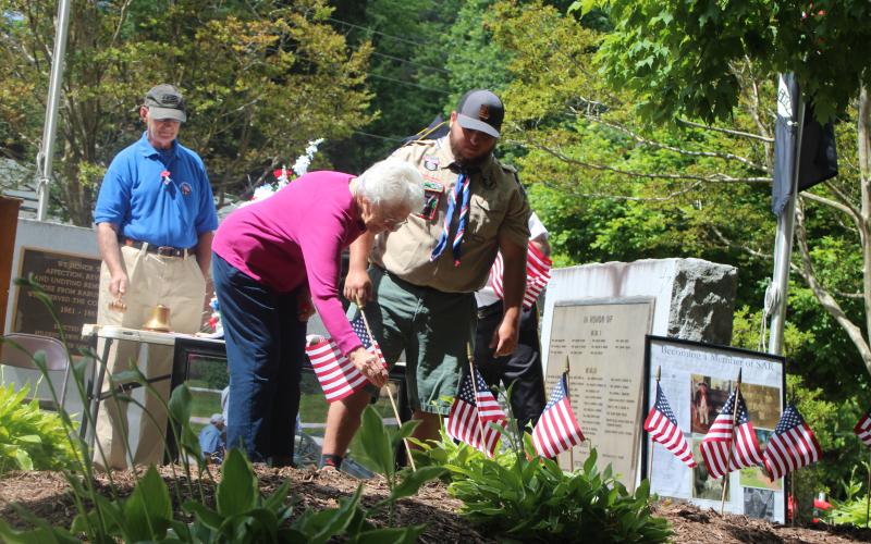 Megan Broome/The Clayton Tribune. Wilma Hoilman places a flag to honor the memory of a veteran close to her who has passed away at Monday’s Memorial Day ceremony. Also pictured are Col. (Ret.) Guy Gober, who was the guest speaker, left, and Eagle Scout Dominic Cross.