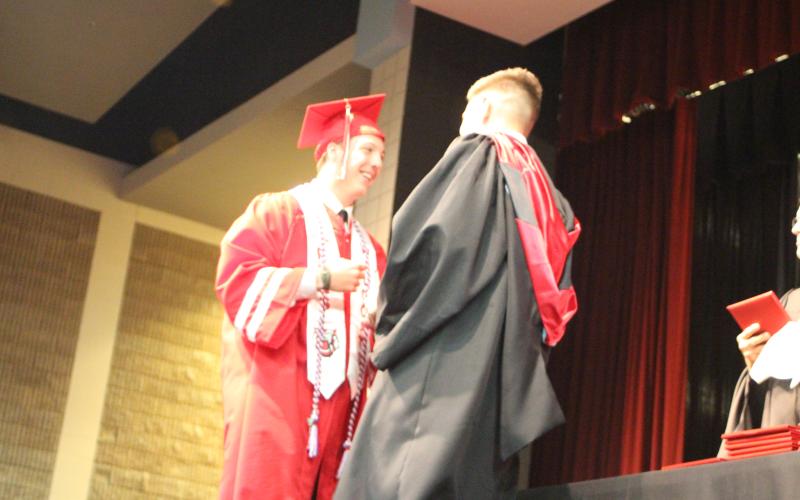 Megan Broome/The Clayton Tribune. Graduate Will Davis gets a fist bump from RCHS Principal Justin Spillers as he receives his diploma at last Friday’s graduation ceremony for the Class of 2021.