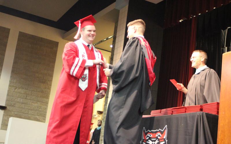 Megan Broome/The Clayton Tribune. Graduate Simon Bass is handed his high school diploma from RCHS Principal Justin Spillers at last Friday’s ceremony.
