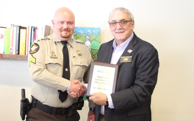 Megan Broome/The Clayton Tribune. Sgt. Riley Owens with the Rabun County Sheriff’s Office, left, is presented with the 2021 Rotary Club of Clayton Officer of the Year award by Rotary President Wayne Knuckles at the club’s meeting held at the Food Bank of Northeast Georgia Teaching Kitchen last Thursday.