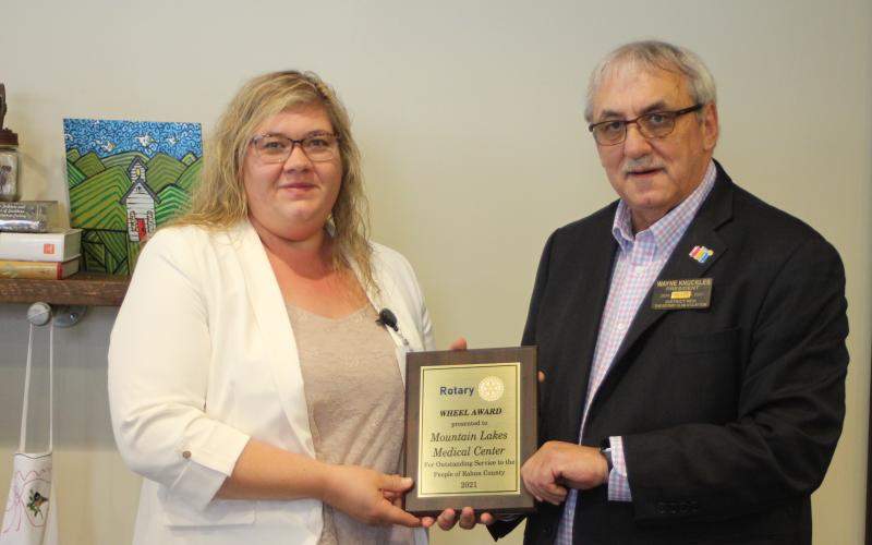 Megan Broome/The Clayton Tribune. Rachel Cowart, chief nursing officer at Mountain Lakes Medical Center, left, accepts the 2021 Rotary Club of Clayton Wheel Award on behalf of Mountain Lakes Medical Center from Rotary President Wayne Knuckles at the club’s meeting held at the Food Bank of Northeast Georgia Teaching Kitchen last Thursday.