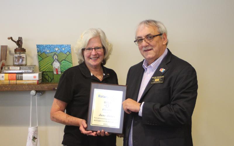 Megan Broome/The Clayton Tribune. Jane Janes, left, is presented with the 2021 Rotary Club of Clayton Gold R. Award by Rotary President Wayne Knuckles at the club’s meeting held at the Food Bank of Northeast Georgia Teaching Kitchen last Thursday.