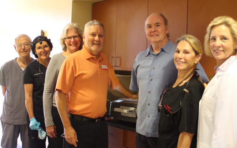 Megan Broome/The Clayton Tribune. Dr. Tom Callahan, left, Dr. Mollie Winston, Jane Janes, Tim Ranney, Dick Newkirk, Suzanne Newkirk and Dr. Janet Dunwoody stand in front of the new flash sterilizer in the Community Dental Clinic at the Rabun County Health Department.