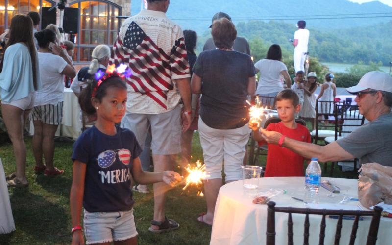 Megan Broome/The Clayton Tribune. Alise Aguilar plays with a sparkler at a patriotic event at the Dillard House on Sunday.