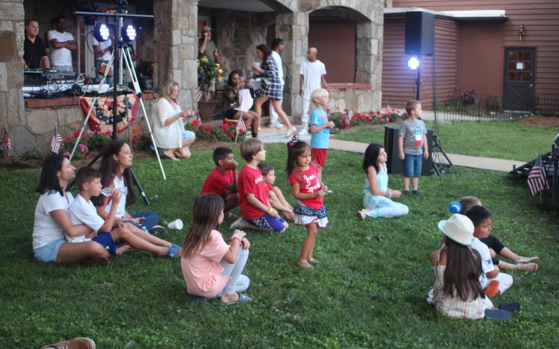 Megan Broome/The Clayton Tribune. Children sit on the lawn of the Rock House in Dillard and listen to live entertainment hosted by The Dillard House on Sunday.
