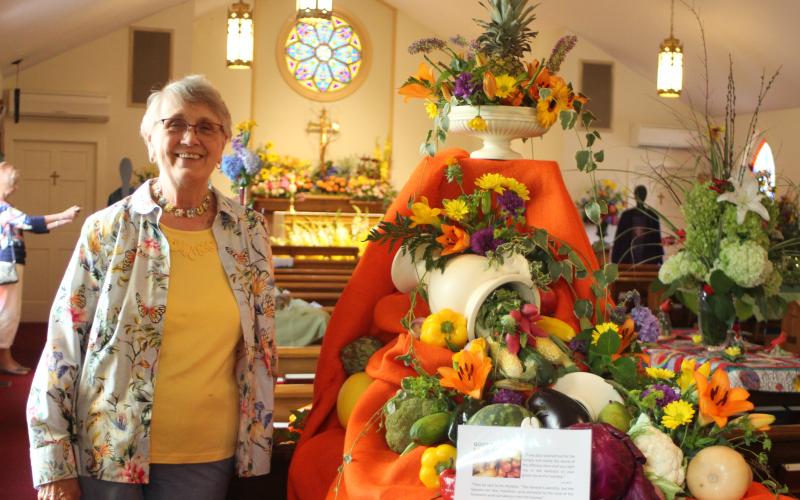 Megan Broome/The Clayton TribunePeggy Melton stands in front of a floral arrangement . depicting “God’s Bounty” at the 14th annual Flower Festival at St. James Episcopal Church on Saturday.  The theme was “God’s Creation: Behold, I make all things new” and floral arrangements were created to represent and celebrate God’s creations.