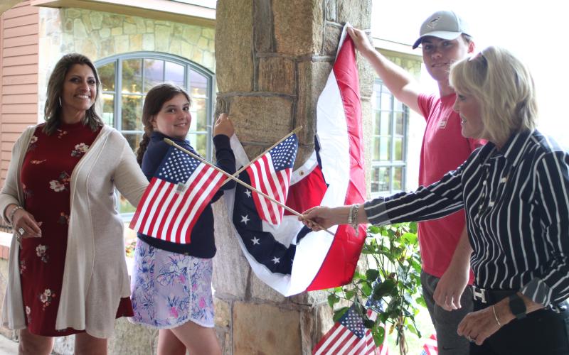 Megan Broome/The Clayton Tribune. Jo Flores, left, Blaire Cross, Dillard Cross and Louise Dillard, owner of The Dillard House, decorate The Rock House at the Dillard House in Dillard on Tuesday to prepare for upcoming Fourth of July festivities. The Dillard House will host a BBQ and live music on Saturday and Sunday.