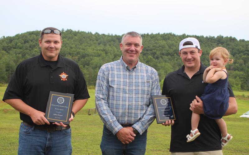 Megan Broome/The Clayton Tribune. Sheriff Chad Nichols, center, presents the Bravery Award to Deputy Jeffrey Hooper, left, and the Life Saving Award to Deputy Brandon Hyer for their roles in going above and beyond their normal duties to help citizens and save lives. Hyer holds his daughter, Blakely Hyer.