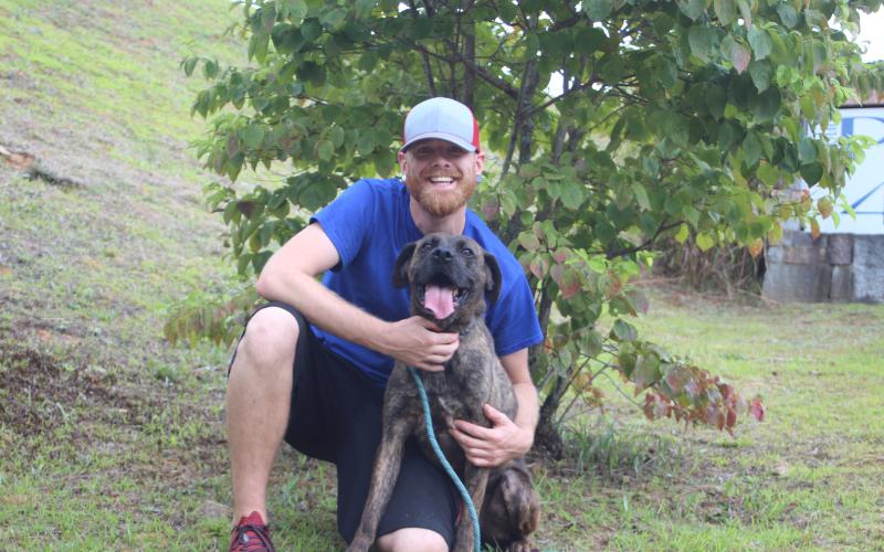 Megan Broome/The Clayton Tribune. Everett Lampros, public relations representative for Paws 4 Life, poses with Eugene, a boxer/hound mix and brindle who’s been at Rabun Paws 4 Life since August 22, 2017. Eugene is looking for his furever home after being rescued from a neglect situation where he was malnourished from inadequate food and water.