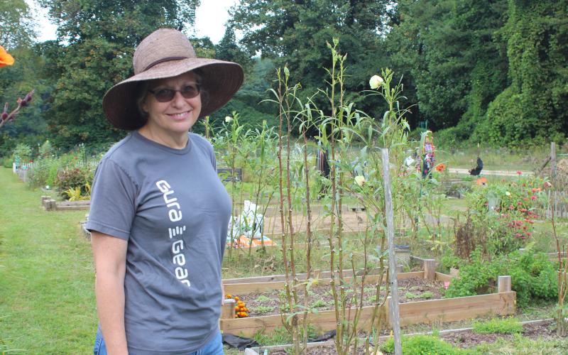 Megan Broome/The Clayton Tribune. Pam Martin poses by flowers and plants on display for the public at the Old School Garden last Saturday.
