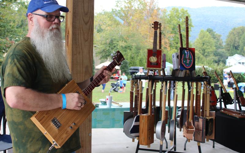 Megan Broome/The Clayton Tribune. Les Barnett plays on of his custom guitars at his booth at the Foxfire Mountaineer Festival last weekend.