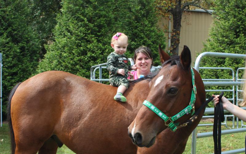 Megan Broome/The Clayton Tribune. Davie Gantt, 11-months-old, and Jennifer Gantt attend the Foxfire Mountaineer Festival last Saturday.