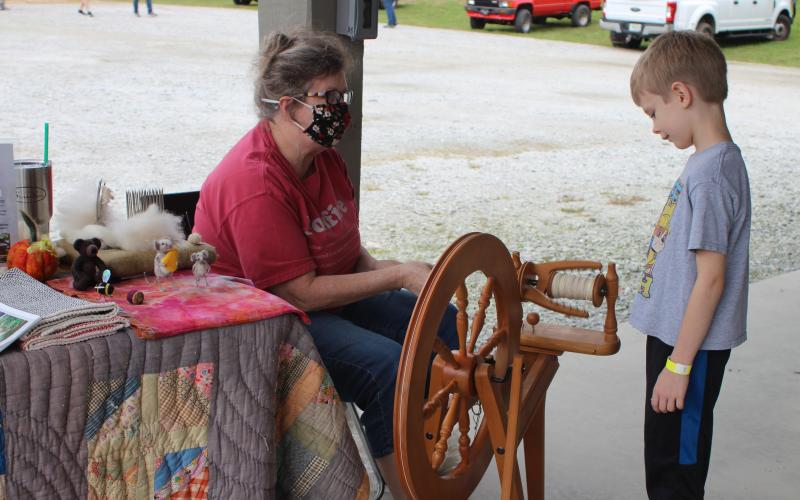 Megan Broome/The Clayton Tribune. Brayden Paul watches as Kelly Coldren spins wool at the Foxfire Mountaineer Festival last weekend.