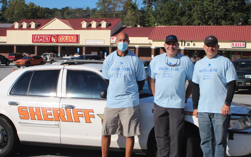 Megan Broome/The Clayton Tribune. James Brim, manager of the Food Bank of Northeast Georgia Mountain Branch, left, Rabun County Sheriff Chad Nichols, and John Hutcheson, pastor of Tabernacle Baptist Church and chaplain for the sheriff's office, participate in the Faith and Blue event last Saturday.