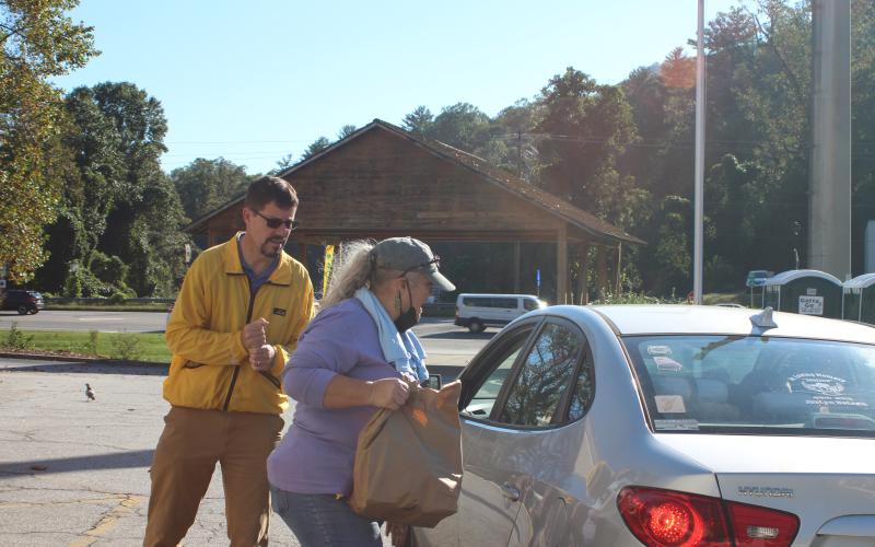 Megan Broome/The Clayton Tribune. Eric Vogelbacher with Knights of Columbus from St. Helena Catholic Church, left, and Shelia Cannon, night advocate at the FAITH shelter, help distribute food at the Faith and Blue event last Saturday.