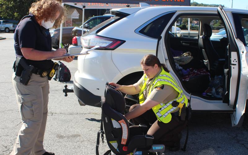 Megan Broome/The Clayton Tribune. Lisa Thompson, coordinator for Safe Kids Rabun County, and Ana Contreras, deputy with the Rabun County Sheriff's Office, check a child's cart seat at the event.