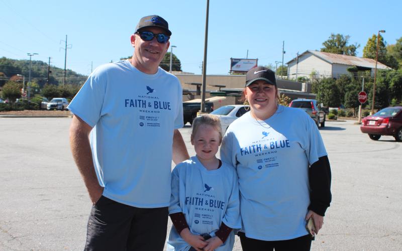 Megan Broome/The Clayton Tribune. Sheriff Chad Nichols, left, Bella Watts, 7, and Ashley York with Freedom Ministries Lighthouse, at the Faith and Blue event last Saturday.