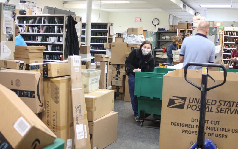 Megan Broome/The Clayton Tribune. Amanda Noffsinger sorts packages at the Clayton Post Office on Monday. The post office is receiving a higher volume of packages than usual for this time of year, receiving an average of 1,000 packages each day, according to Colby Nichols, acting supervisor for the Clayton Post Office.