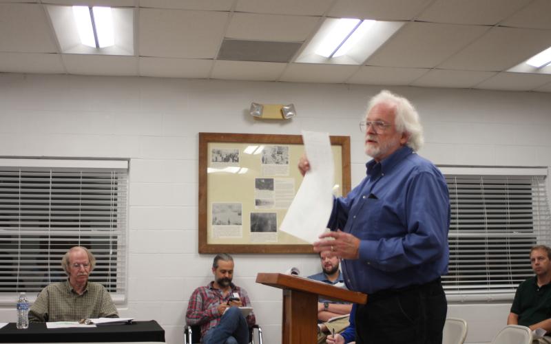 Megan Broome/The Clayton Tribune. Tallulah Falls citizen Keith Nelms speaks to town council members last Thursday in opposition to rezoning 1.12 and 4.577 acre parcels on River St. and Hickory Nut Mountain Rd. from Single Family Residential (R1) to Business District (BD) for the development of short-term vacation rentals by J&amp;D Irvin Holdings, LLC. Larry Hamilton, council member, left, and Clint and Brian Irvin, of J&amp;D Irvin Holdings, LLC, back, listen to public comment on the matter.