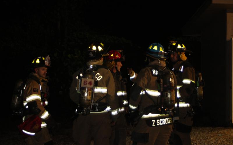 Megan Broome/The Clayton Tribune. Firefighters discuss strategies and tactics at the live fire training at Station 4.