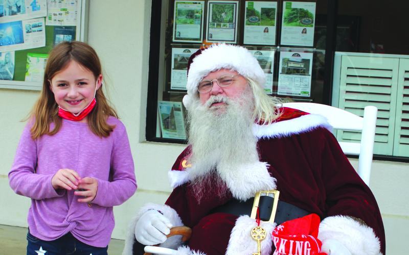 Megan Broome/The Clayton Tribune. Winni Cox, 8, tells Santa her Christmas wishes at the Better Homes and Gardens Real Estate company in Clayton on Dec. 17.