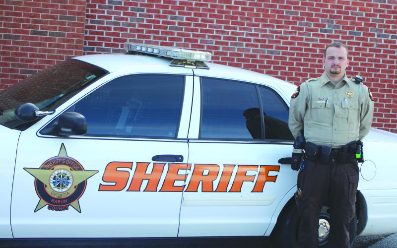 Megan Broome/The Clayton Tribune. Rabun County Sheriff’s Office Deputy Dakota Dills stands next to his patrol car. Dills was named the 2021 Deputy of the Year.