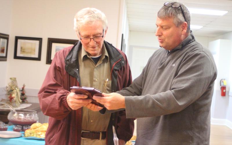 Megan Broome/The Clayton Tribune. Dillard City Council member Claude Dillard, right, presents Mayor Bill Robinson with a plaque on behalf of the city, thanking him for his 20 years of service as mayor, at a reception following Tuesday’s council meeting.