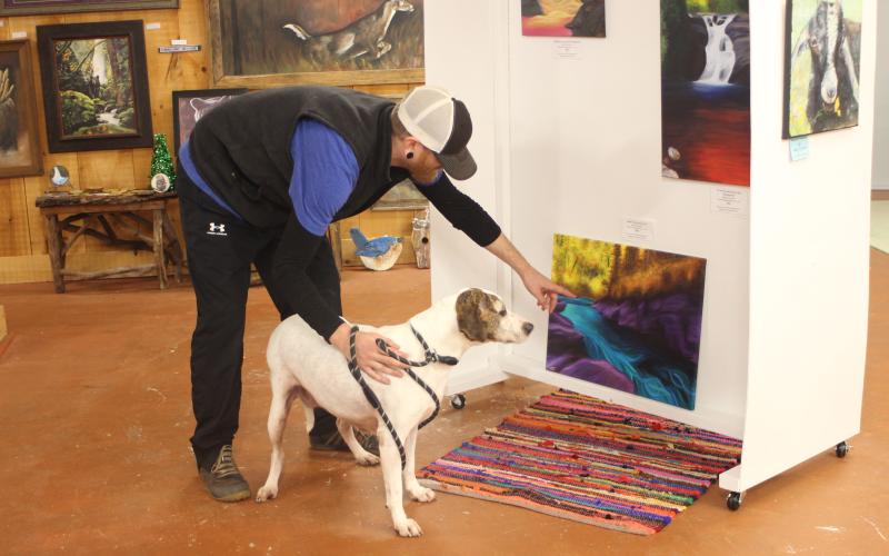 Megan Broome/The Clayton Tribune. Everett Lampros, shelter public relations manager, takes Buffy around Gallery 441 in Dillard during the Art Sale and Clothing Rummage set up by Gallery 441 and Tallulah Gorgeous in Dillard to raise money for Paws 4 Life. Buffy was one of the animals available for adoption at the event.
